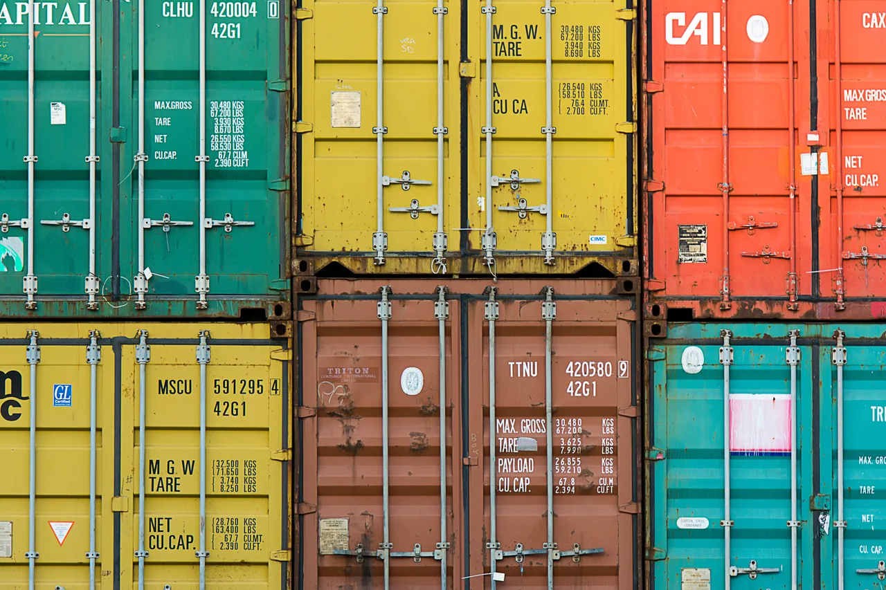 Rows of shipping container doors in different colours showing gross weight, tare and capacity markings