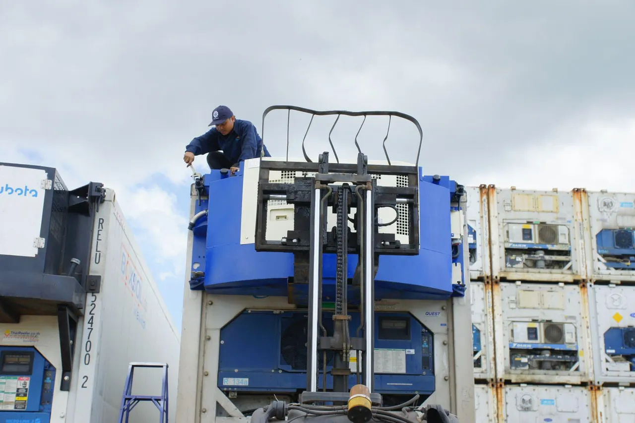 Technician servicing a container refrigeration generator set in a container yard