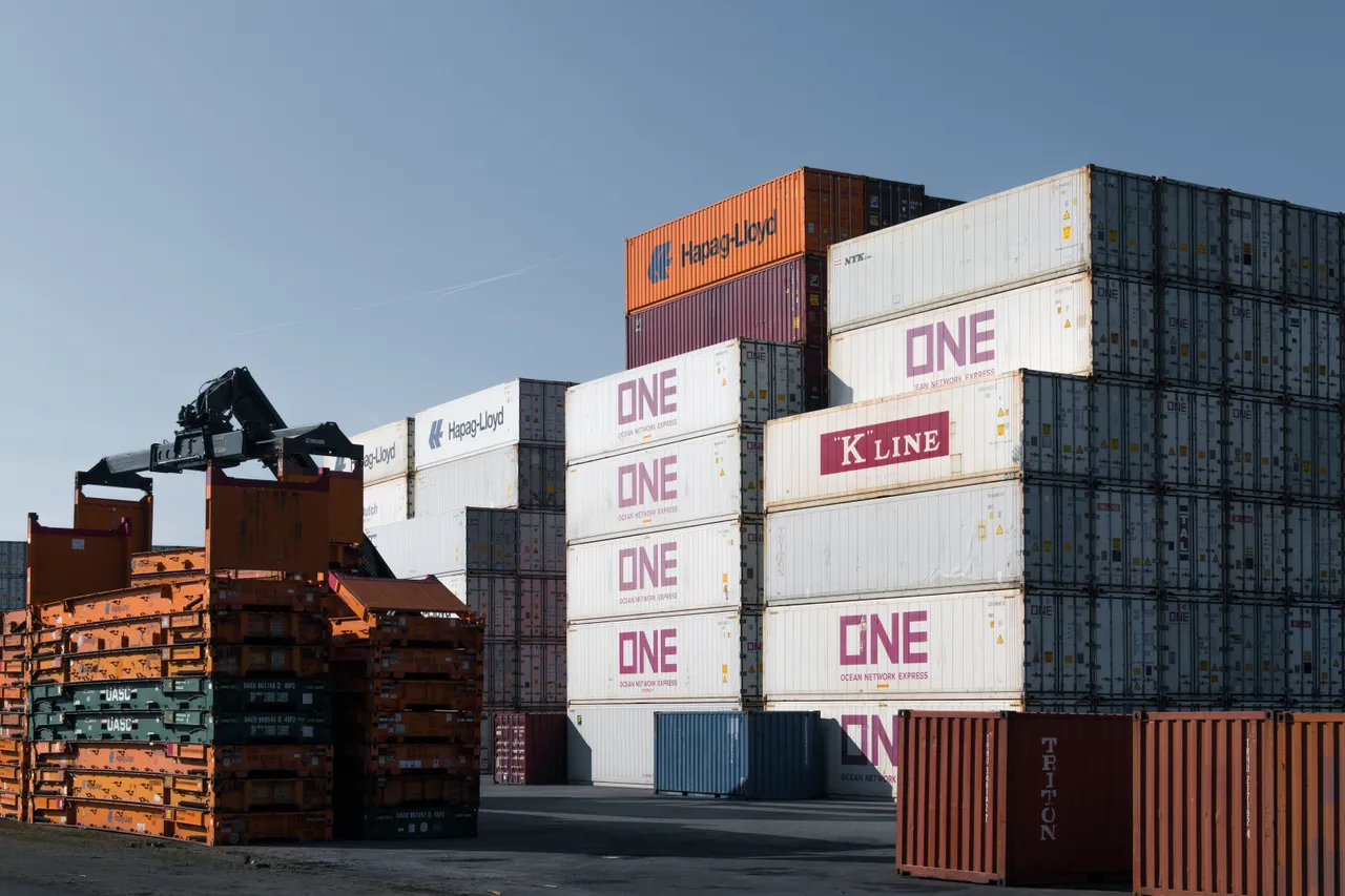 Wide view of a container depot with stacked refrigerated containers and handling equipment